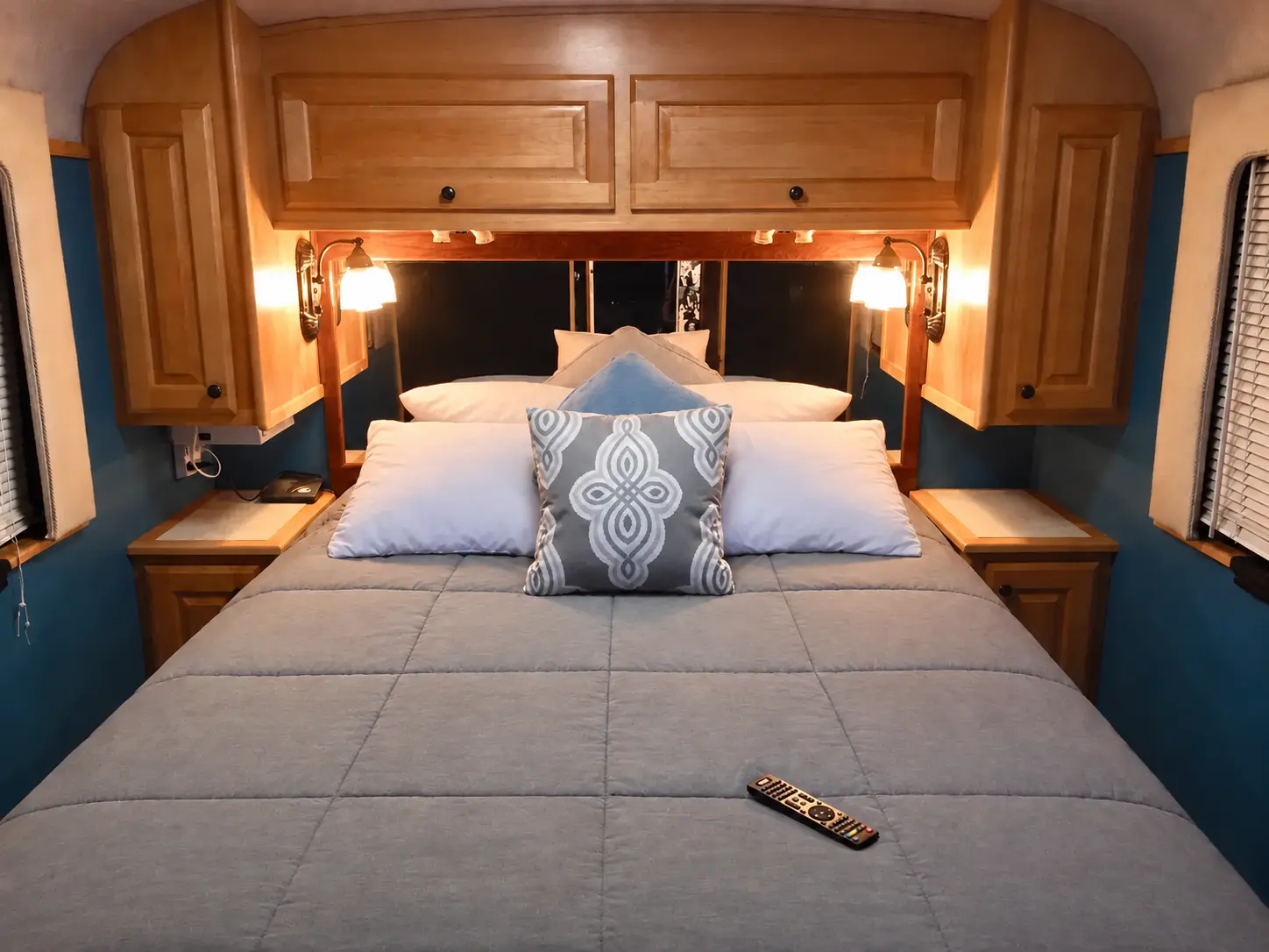Rear queen bedroom with a neatly arranged symmetrical pillow display inside the vintage Eagle tour bus